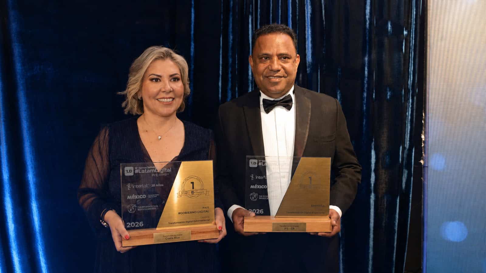 Funcionarios sostienen reconocimientos internacionales durante ceremonia de premiación por transformación digital en América Latina.
