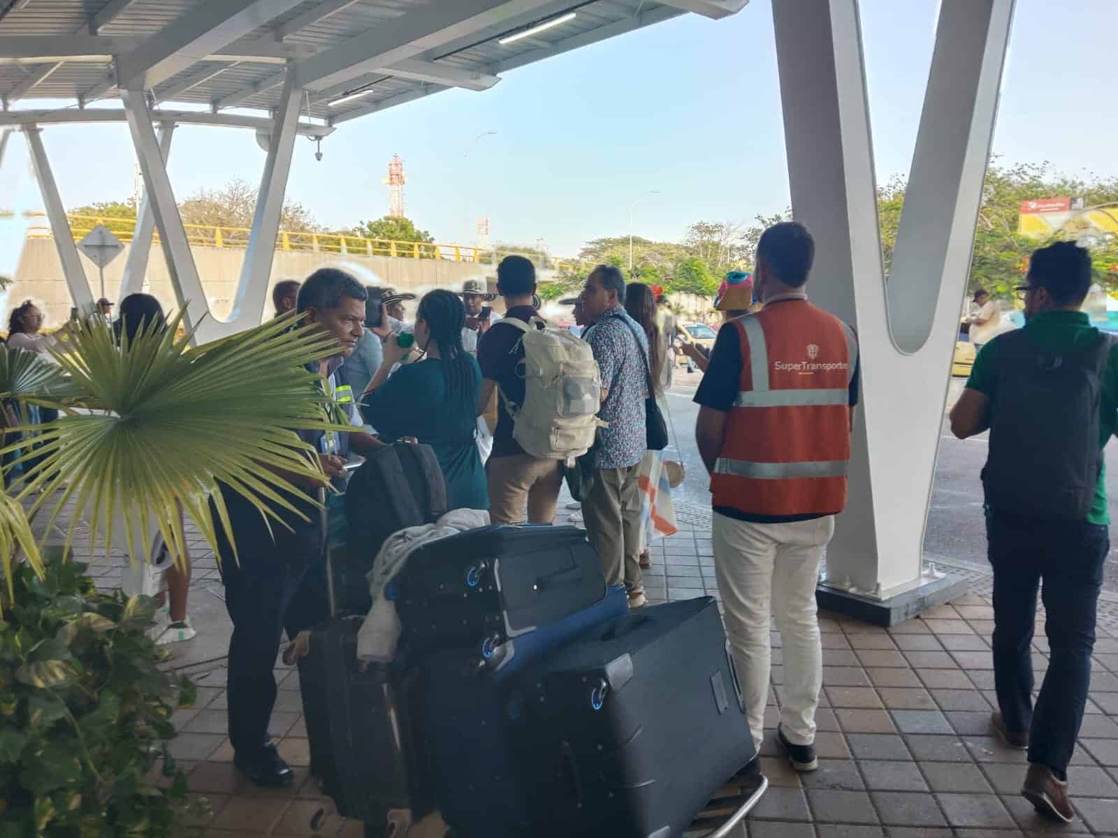 Funcionario de la Superintendencia de Transporte orienta a viajeros en la zona de ingreso de una terminal aérea, verificando condiciones de atención y prestación del servicio.