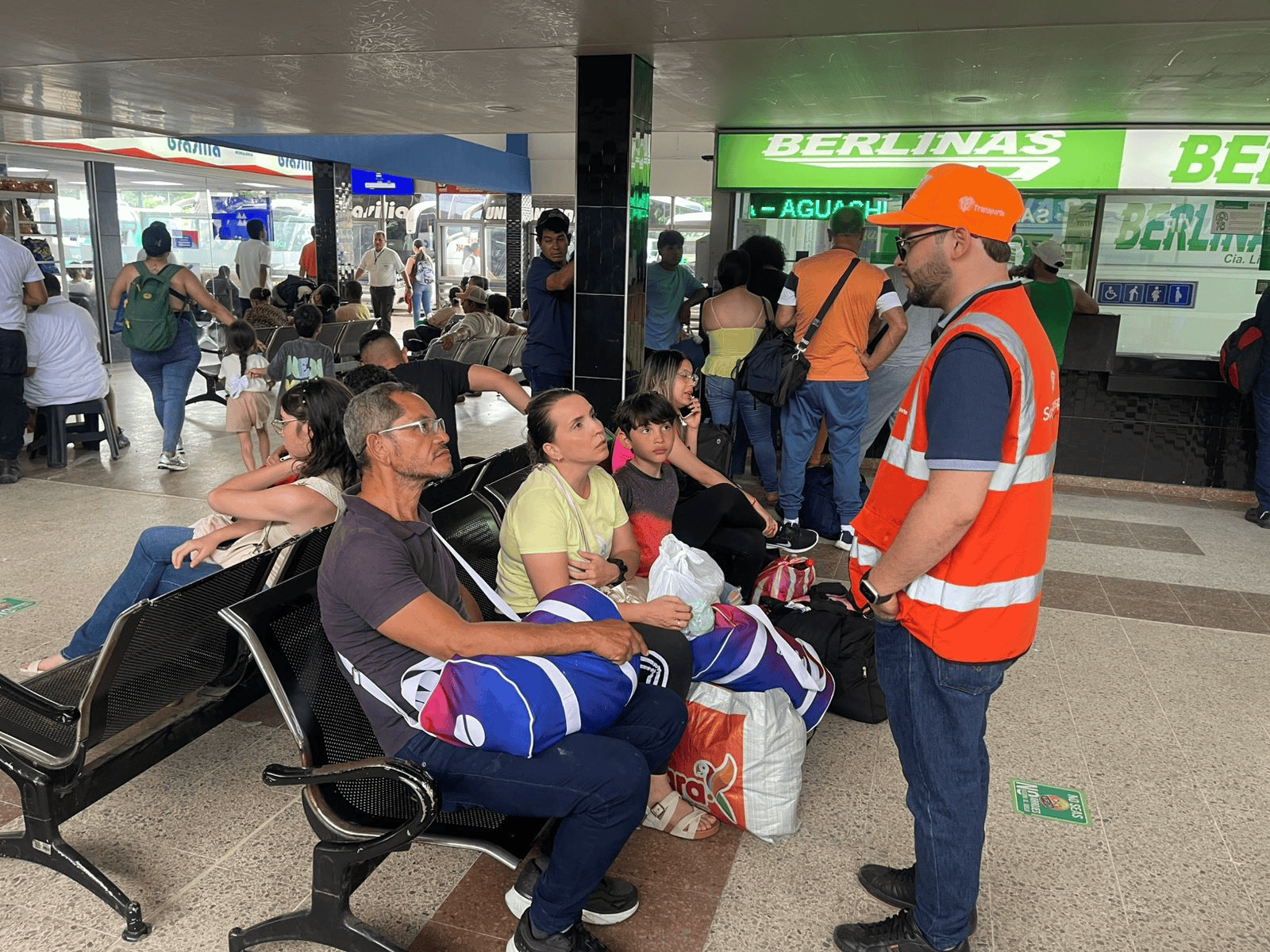 Funcionario de la Superintendencia de Transporte brinda orientación a usuarios en una terminal terrestre durante una jornada de atención al ciudadano.